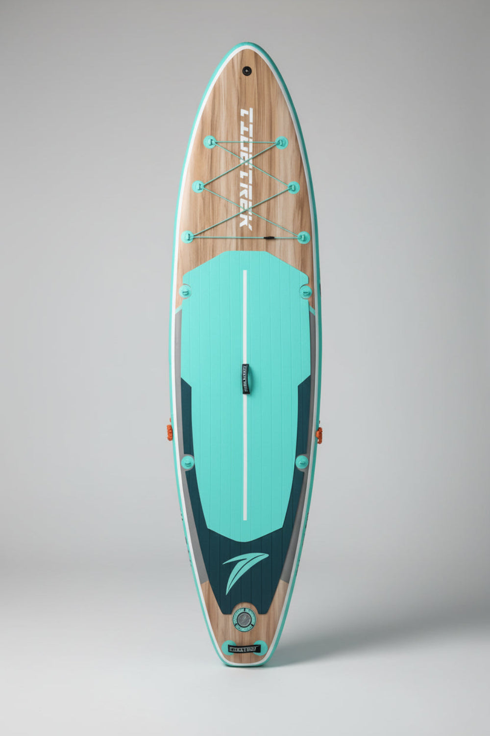 A TIDE TREK stand-up paddleboard standing vertically on cardboard in front of a light blue-gray metal warehouse building under a cloudy sky.